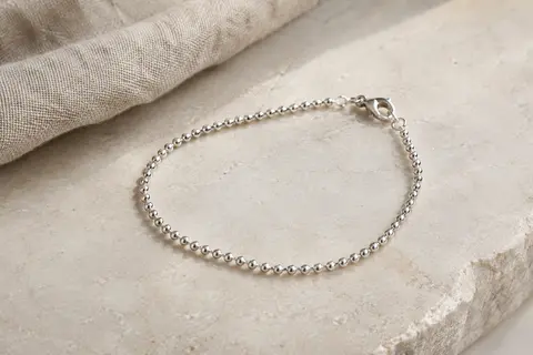 Bracelet Amberta en argent 925 à maille boule fine et fermoir mousqueton, posé sur une surface claire.