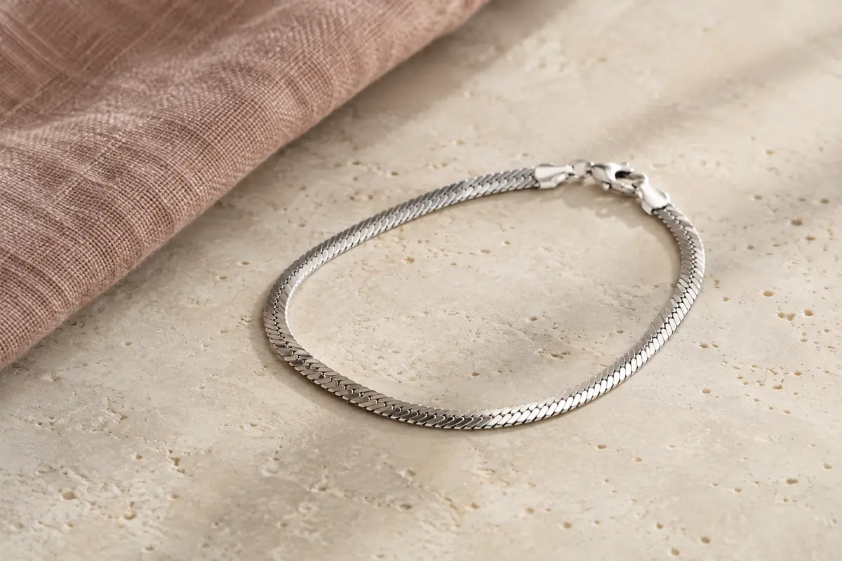Bracelet Amberta en argent 925 à maille miroir, présenté seul sur une surface minérale ivoire.