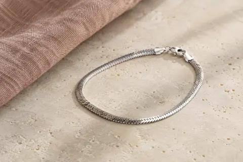Bracelet Amberta en argent 925 à maille miroir, présenté seul sur une surface minérale ivoire.