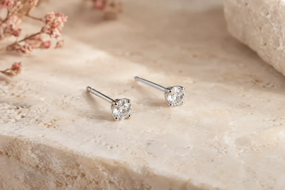 Paire de petites puces Amberta en argent 925 avec zircones cubiques, posées sur une surface claire.