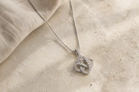 Collier en argent sterling avec pendentif entrelacé orné de zircone cubique, posé sur une surface claire.