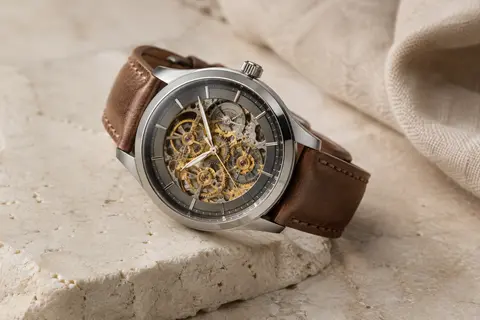 Montre BENYAR à cadran squelette gris fumé et détails dorés, avec boîtier acier et bracelet en cuir marron.