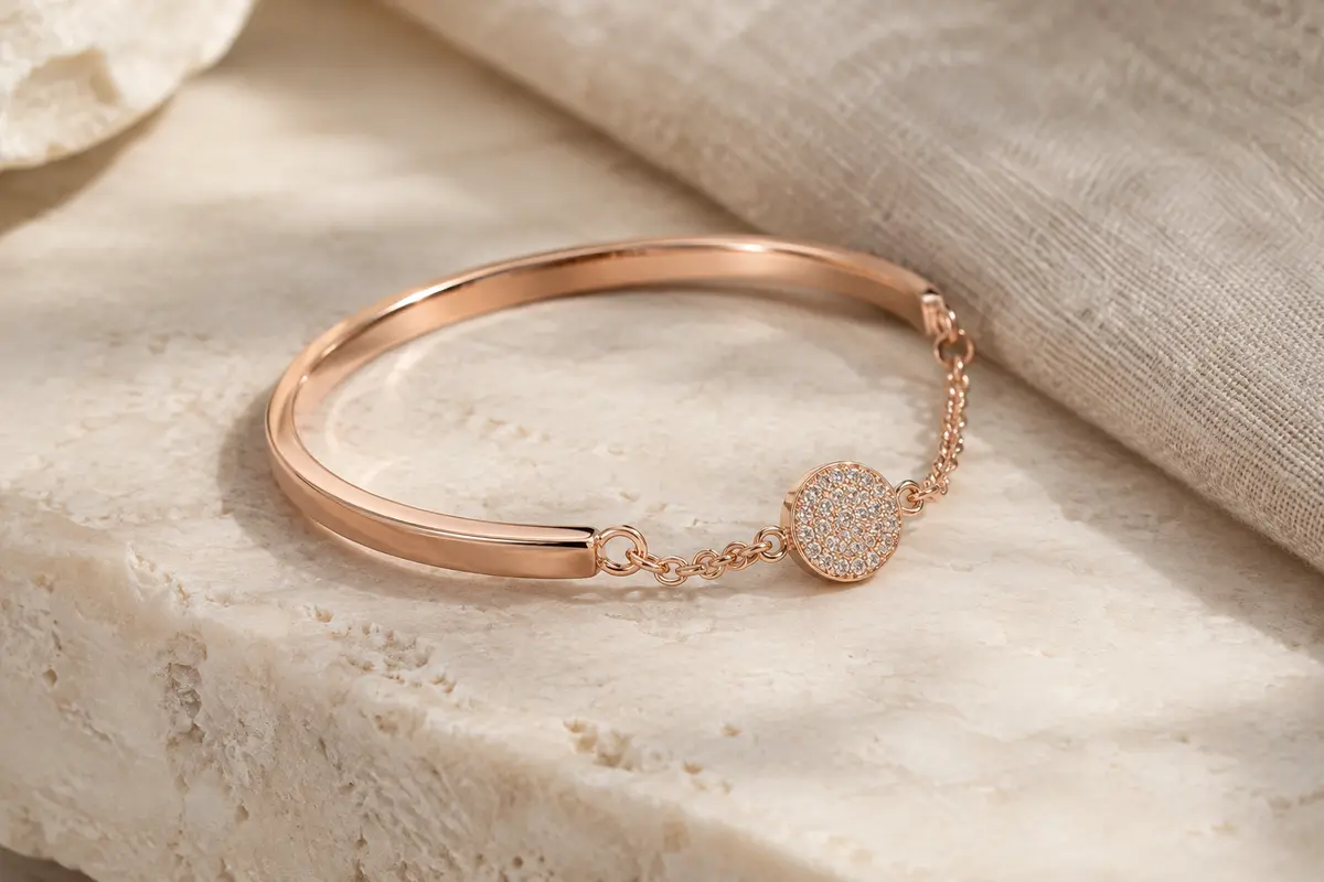 Bracelet jonc rigide au ton or rosé avec chaîne délicate et disque serti de cristaux