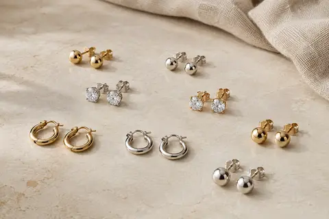 Ensemble de petits clous d’oreilles et mini créoles en acier, présenté sur une surface claire.