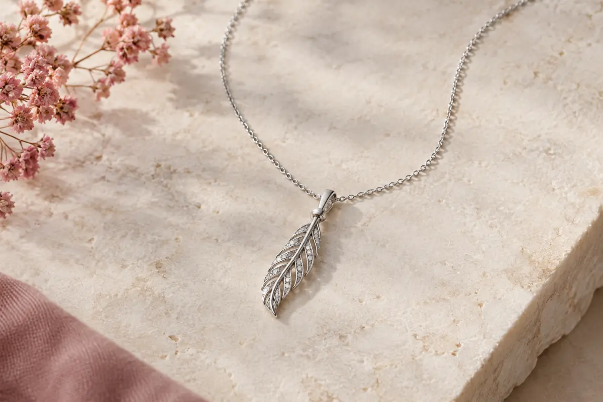Collier Elli en argent 925 avec pendentif plume orné de cristaux, posé sur une surface claire.