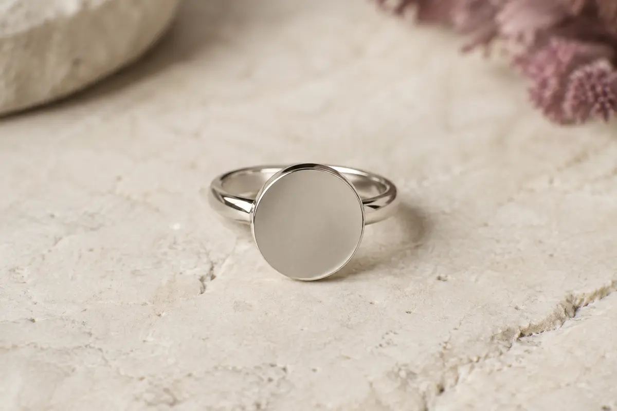 Bague en acier Emotional avec médaille ronde de 12 mm posée sur une surface claire