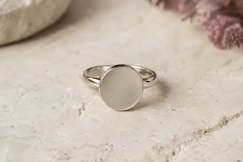 Bague en acier Emotional avec médaille ronde de 12 mm posée sur une surface claire