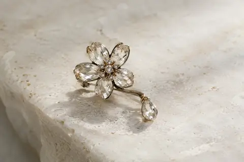 Broche EVER FAITH en forme de fleur avec une goutte, présentée seule sur du lin naturel clair.