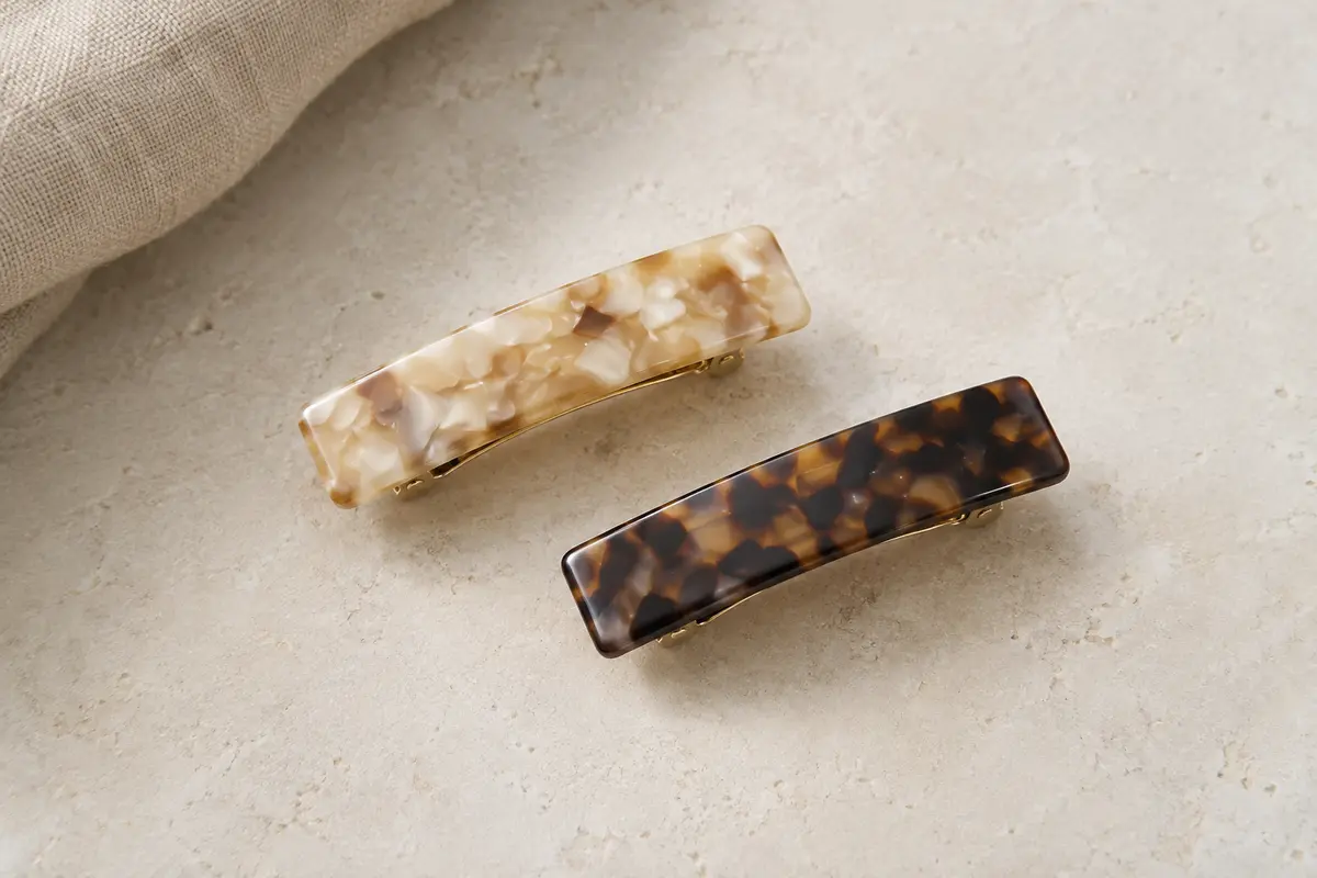 Deux barrettes rectangulaires en acétate à motifs écaille clair et foncé, posées sur une surface claire.