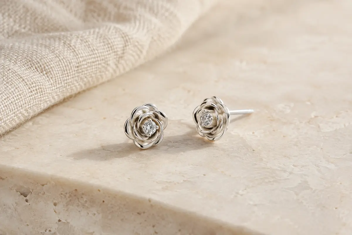 Paire de puces d’oreilles en forme de rose avec une zircone centrale et des tiges indiquées en argent 925.