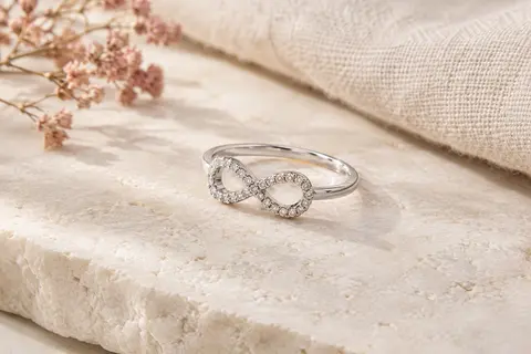 Bague en argent au motif infini serti de zircons cubiques, présentée sur une surface claire.