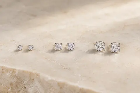Trois paires de puces d’oreilles en acier inoxydable ornées de zircones blanches, disposées sur une surface claire.