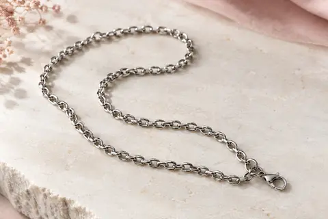 Chaîne à maillons argentée en acier inoxydable avec fermoir mousqueton, disposée sur une surface claire.