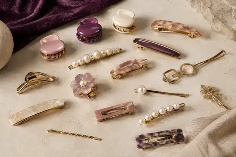 Assortiment de pinces et barrettes Mehayi multicolores en résine, imitation perle et métal, disposées sur une surface claire.