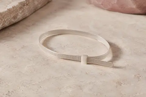 Jauge de doigt en plastique formée en boucle et posée seule sur une surface minérale claire.