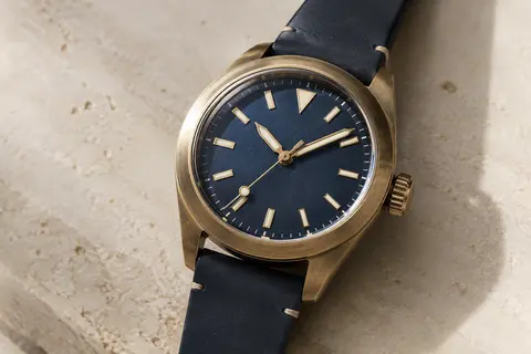 Montre automatique masculine d’inspiration marine photographiée seule sur une surface minérale claire.
