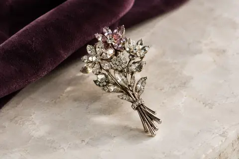 Broche bouquet Oenothera en alliage et strass posée sur une surface claire près d’un velours prune