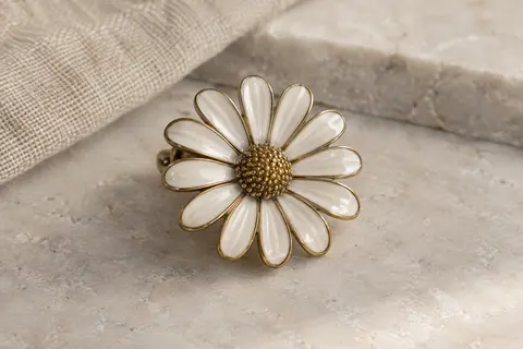 Broche marguerite Oenothera en alliage de zinc émaillé présentée sur une surface claire