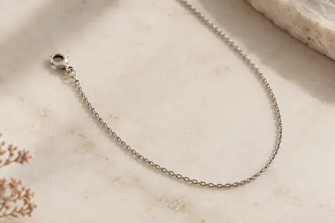 Chaîne de collier argentée en acier inoxydable, disposée seule sur une surface claire