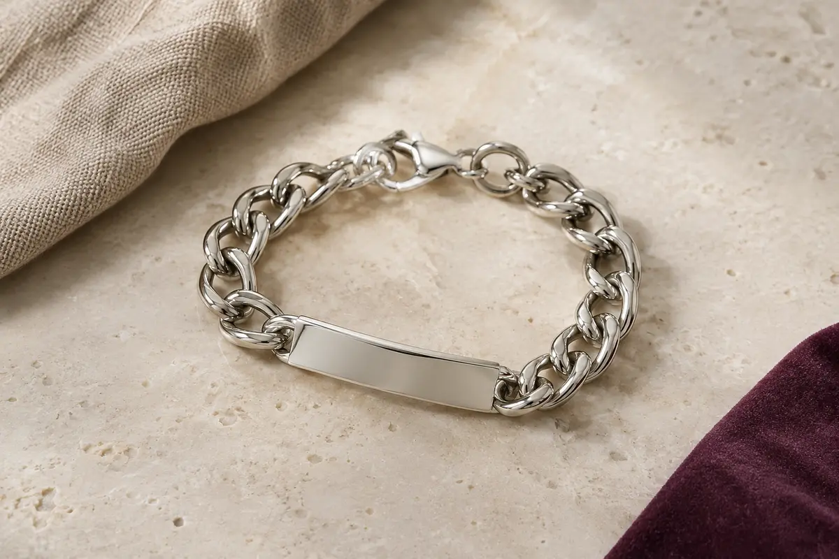 Bracelet chaîne argenté à gros maillons avec plaque horizontale, posé sur une surface minérale claire