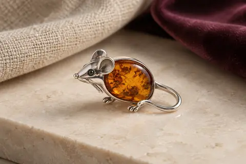 Broche en forme de souris en argent 925, ornée d’une pièce d’ambre baltique aux tons chauds.