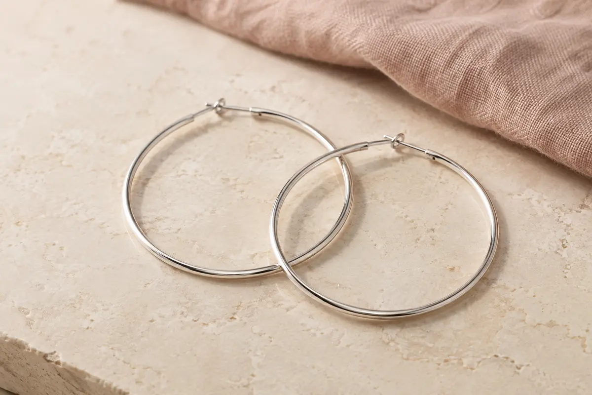 Paire de créoles rondes en argent 925, sans pierre, présentées sur une surface minérale claire