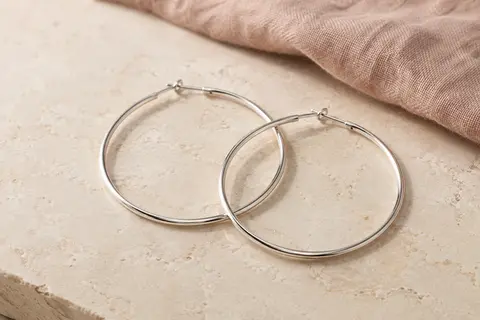 Paire de créoles rondes en argent 925, sans pierre, présentées sur une surface minérale claire