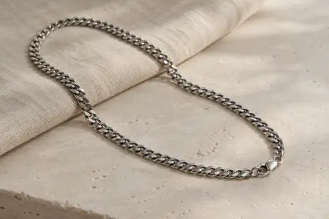 Chaîne gourmette à maille cubain en acier inoxydable présentée seule sur du lin clair