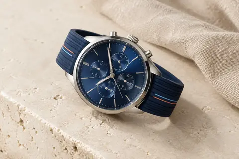 Montre à quartz au cadran bleu marine et bracelet en silicone rayé, posée sur une surface minérale claire.