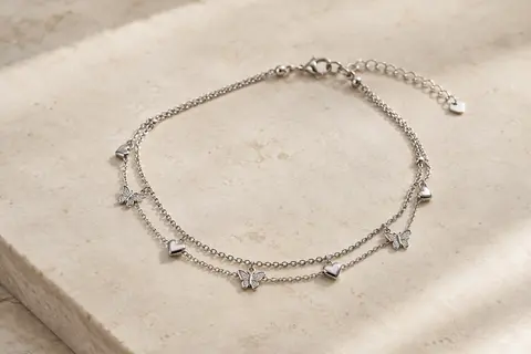 Bracelet de cheville argenté à double chaîne, orné de motifs de papillon et de cœur.
